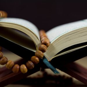 An open Quran with prayer beads on a wooden stand, symbolizing faith and spirituality.