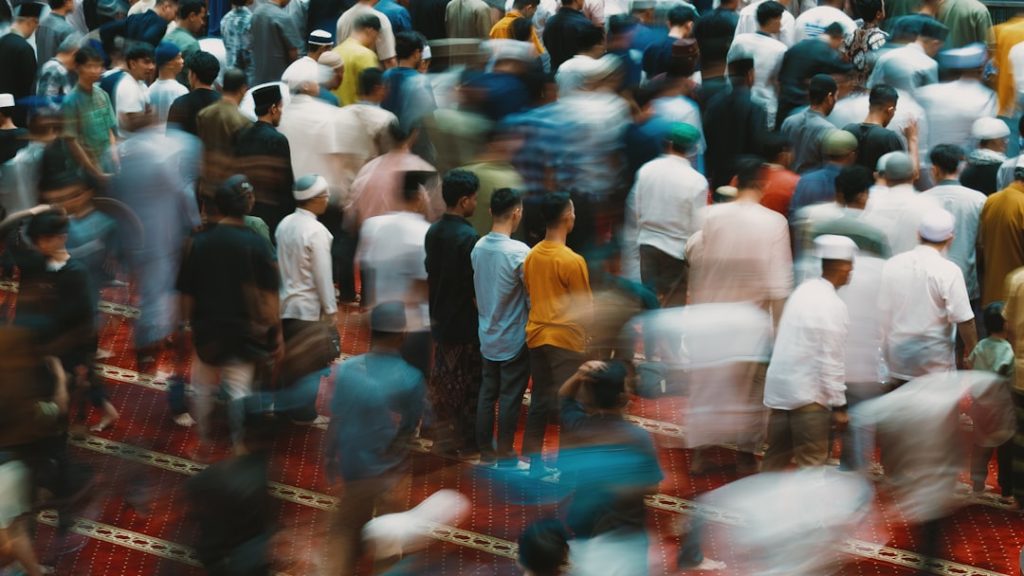people-are-gathered-likely-in-prayer-or-worship-3allehm8jsu Worshippers begin to form organized rows for prayer on a richly patterned red carpet, embodying discipline and unity during a religious gathering.